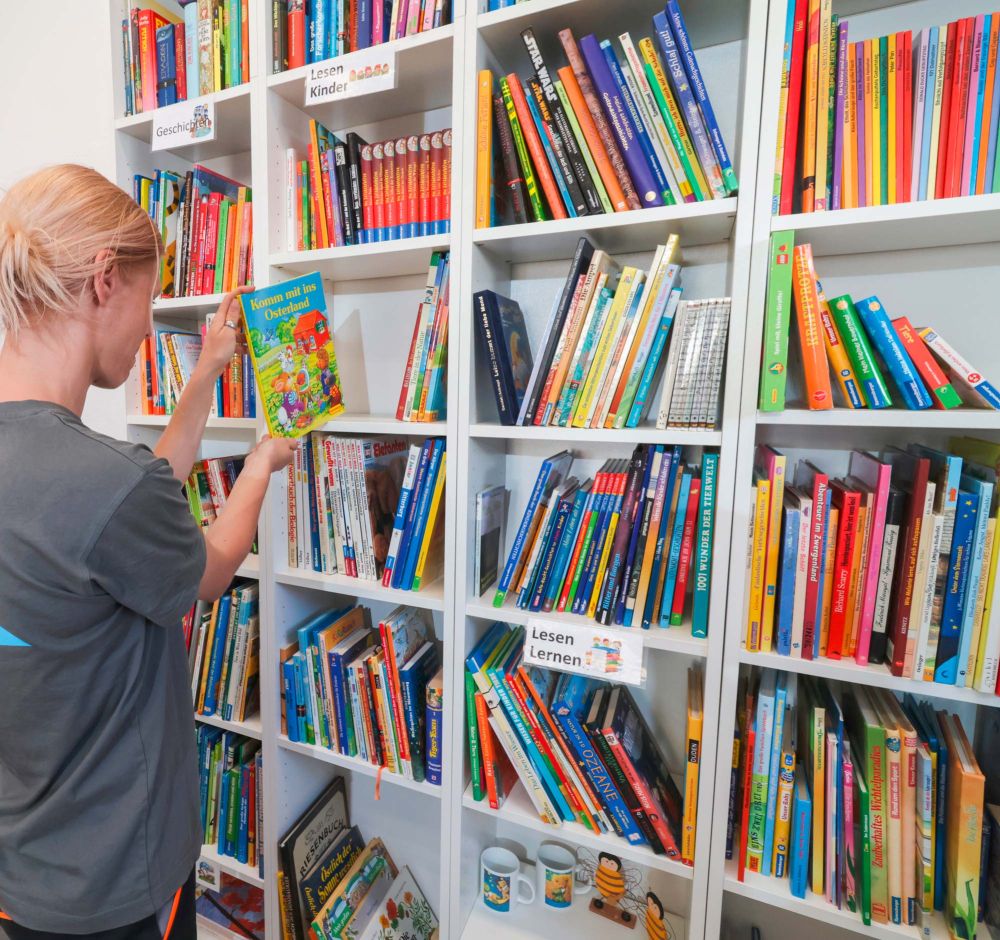 Frau sortiert Bücher ins Regal