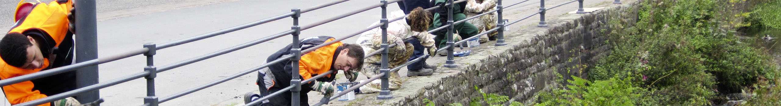 Digeno-Mitarbeiter streichen ein städtisches Geländer.